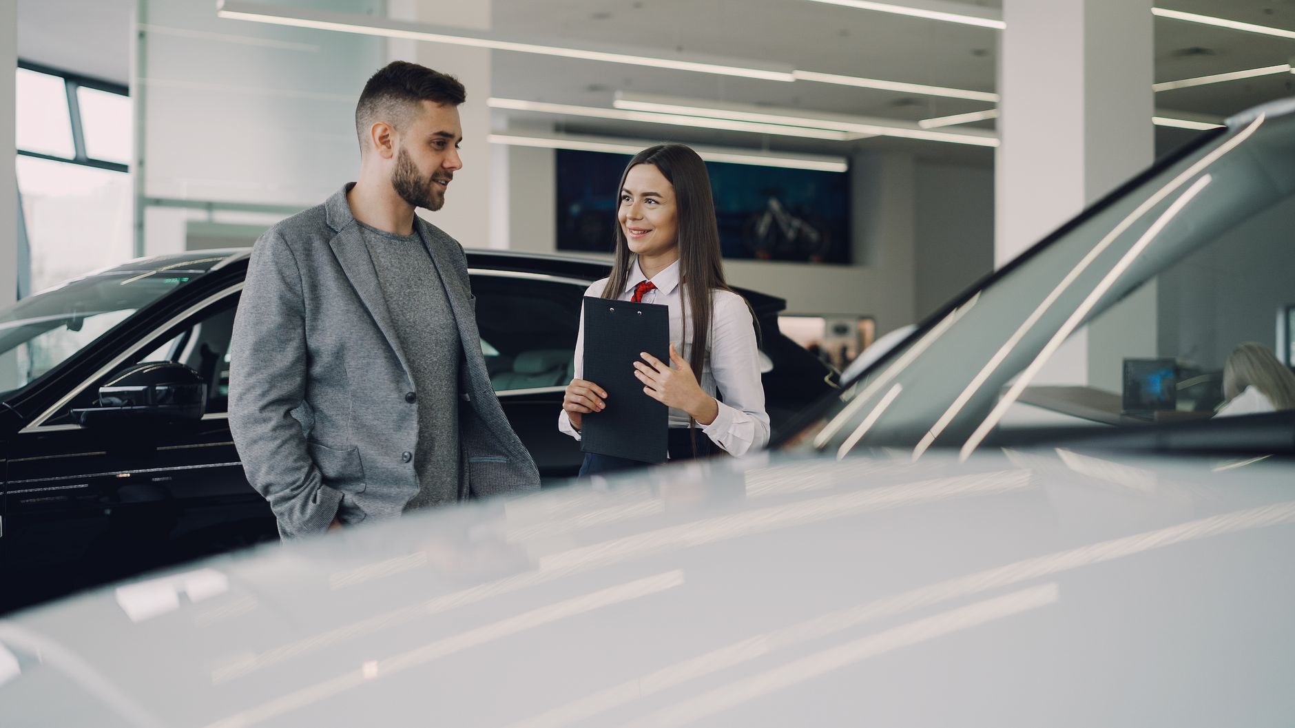 Ilustrasi: Man consults with salesperson in modern car dealership showroom.