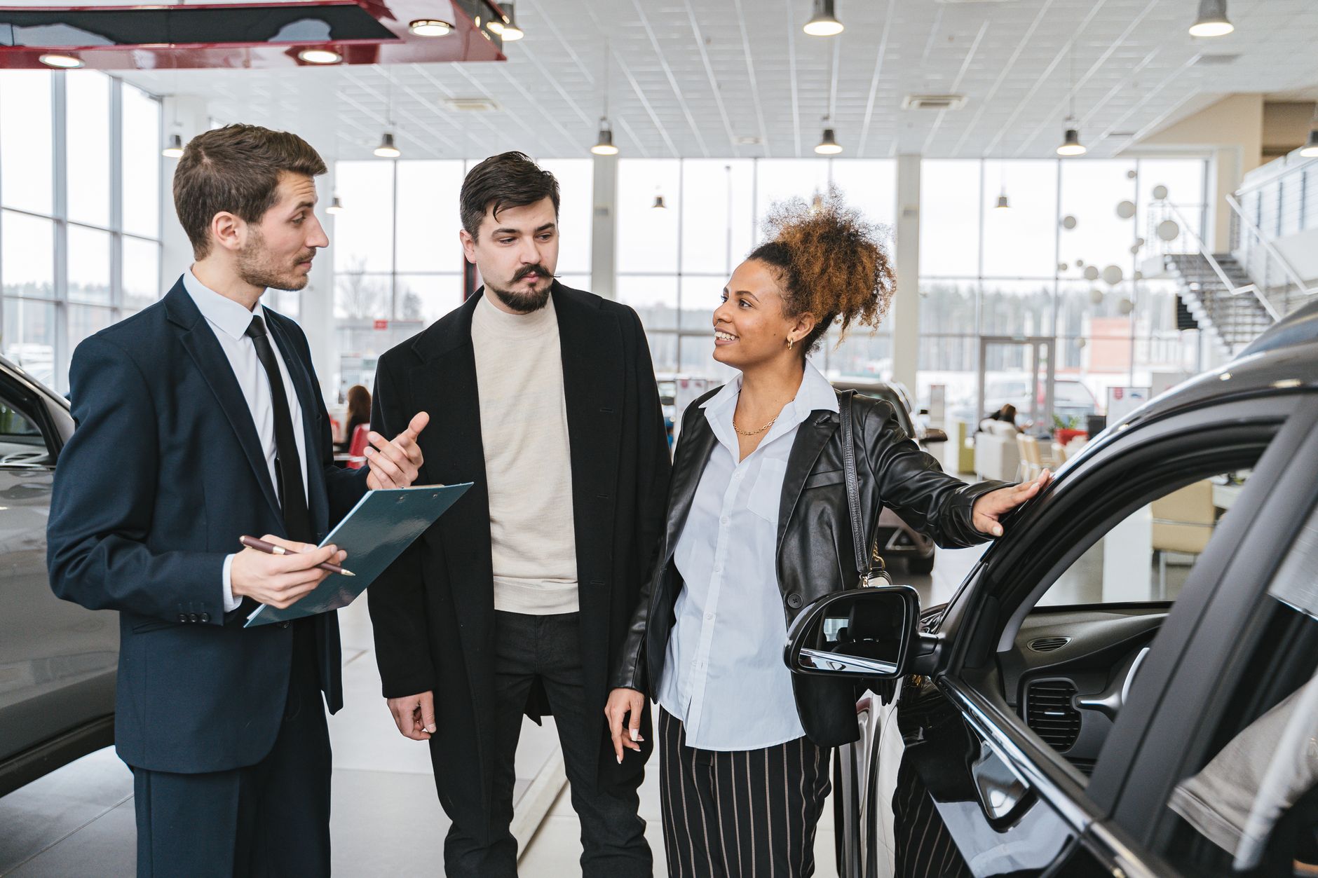 Ilustrasi: A diverse team of adults discussing a car purchase in a dealership showroom.
