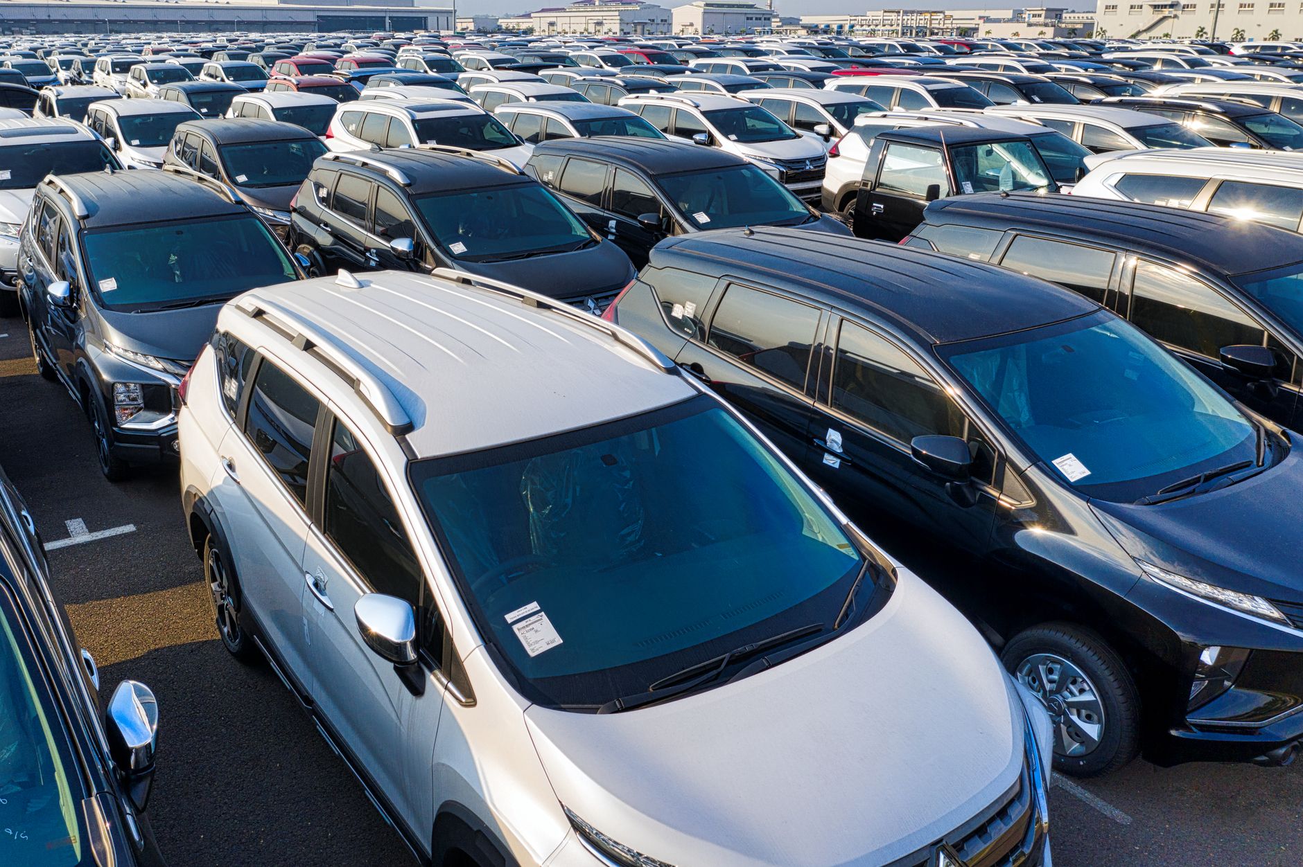 Ilustrasi: Modern sparkling clean new automobiles on asphalt parking near factory of manufacture in daytime
