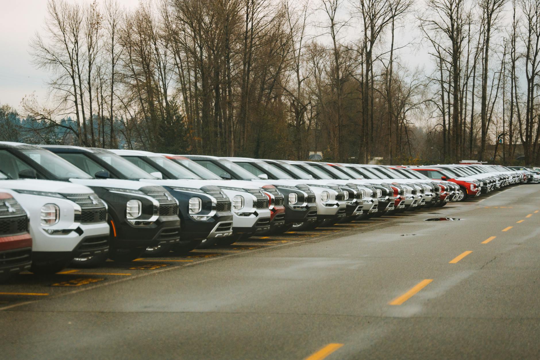 Ilustrasi: A line of brand new SUVs in an outdoor parking lot during a cloudy day.