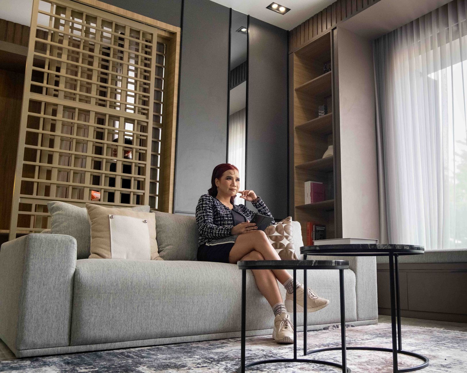 Ilustrasi: Woman sitting comfortably in a modern living room in Jakarta, Indonesia, enjoying leisure time.