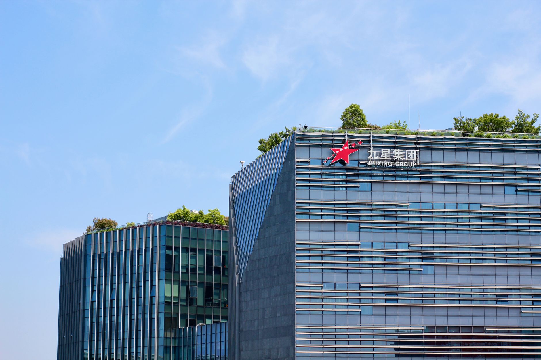 Ilustrasi: Contemporary corporate building featuring green rooftop and modern architecture against blue sky.