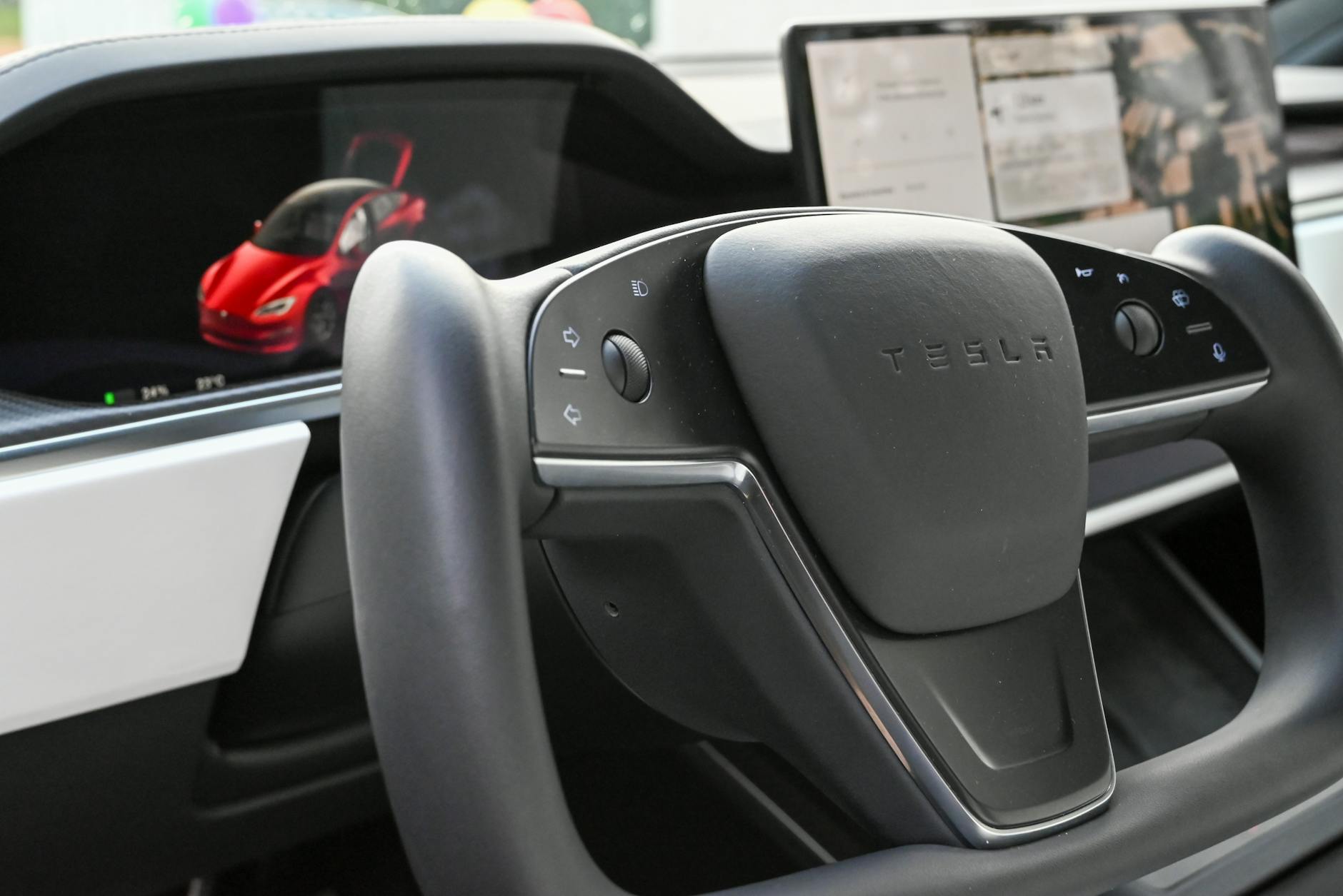 Ilustrasi: Close-up of a modern Tesla steering wheel and digital dashboard inside an electric car.