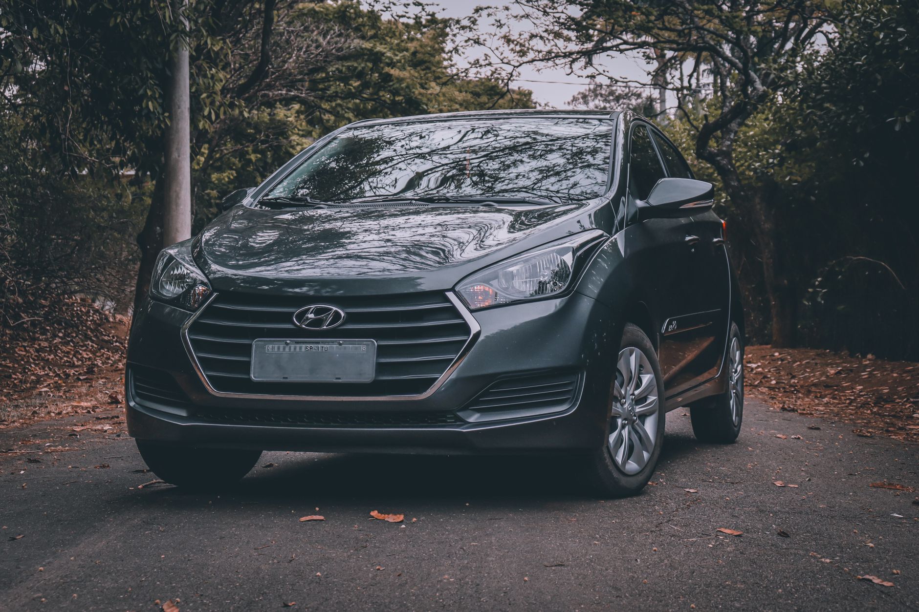 Ilustrasi: Elegant black Hyundai car parked on a scenic road surrounded by trees, showcasing a modern automotive design.