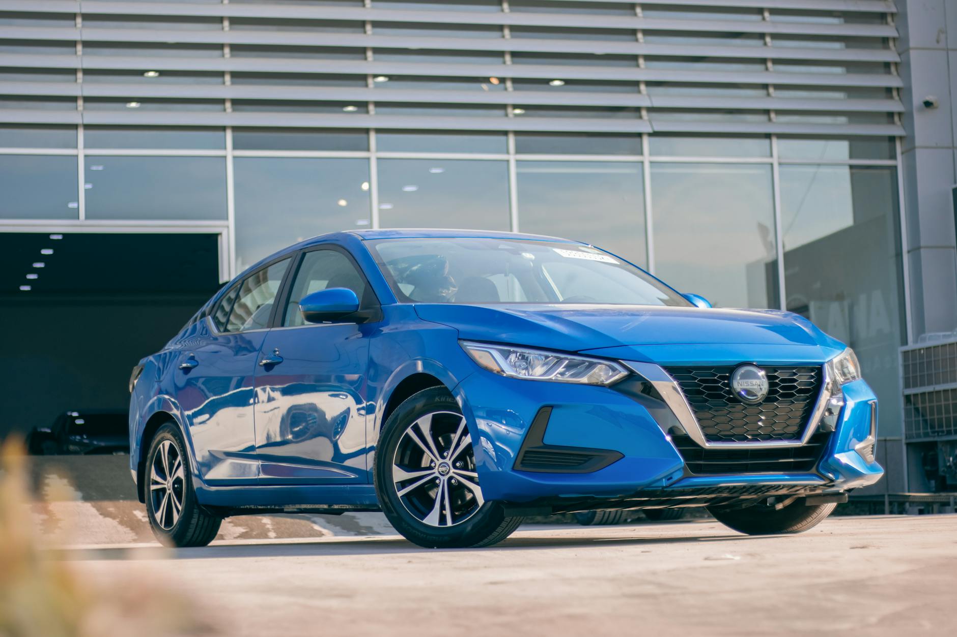 Ilustrasi: Front view of a modern blue Nissan Sentra parked at a dealership, showcasing its sleek design.