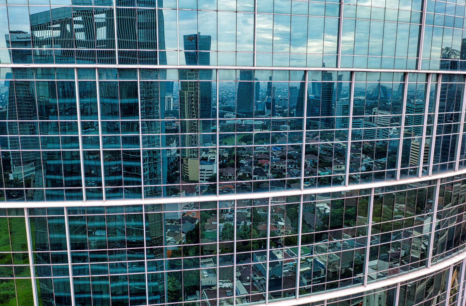 Ilustrasi: Glass facade of a skyscraper reflecting the cityscape of Jakarta, Indonesia on a clear day.