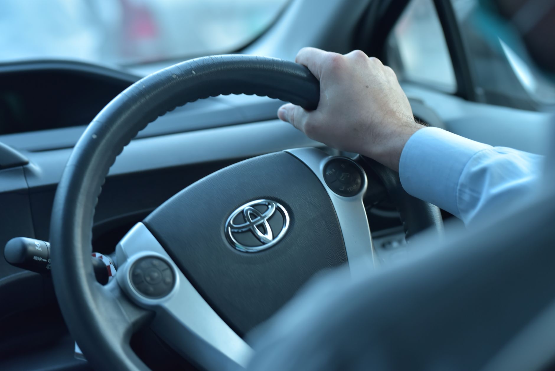 Ilustrasi: Close-up view of a hand gripping a Toyota steering wheel in a car interior, Faisalabad, Pakistan.