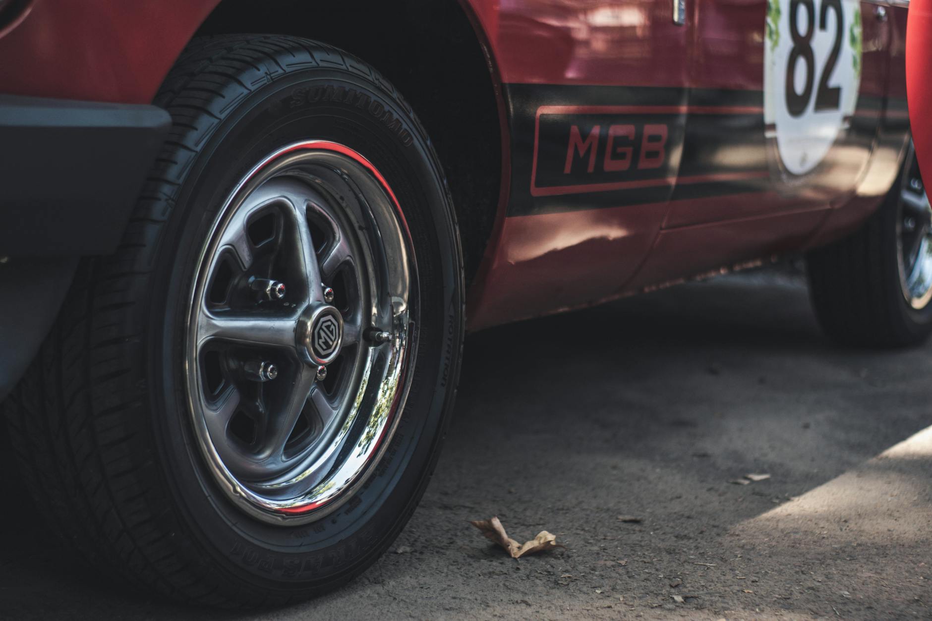 Ilustrasi: Detailed close-up of a classic red MGB car's wheel and rim capturing the vintage design.