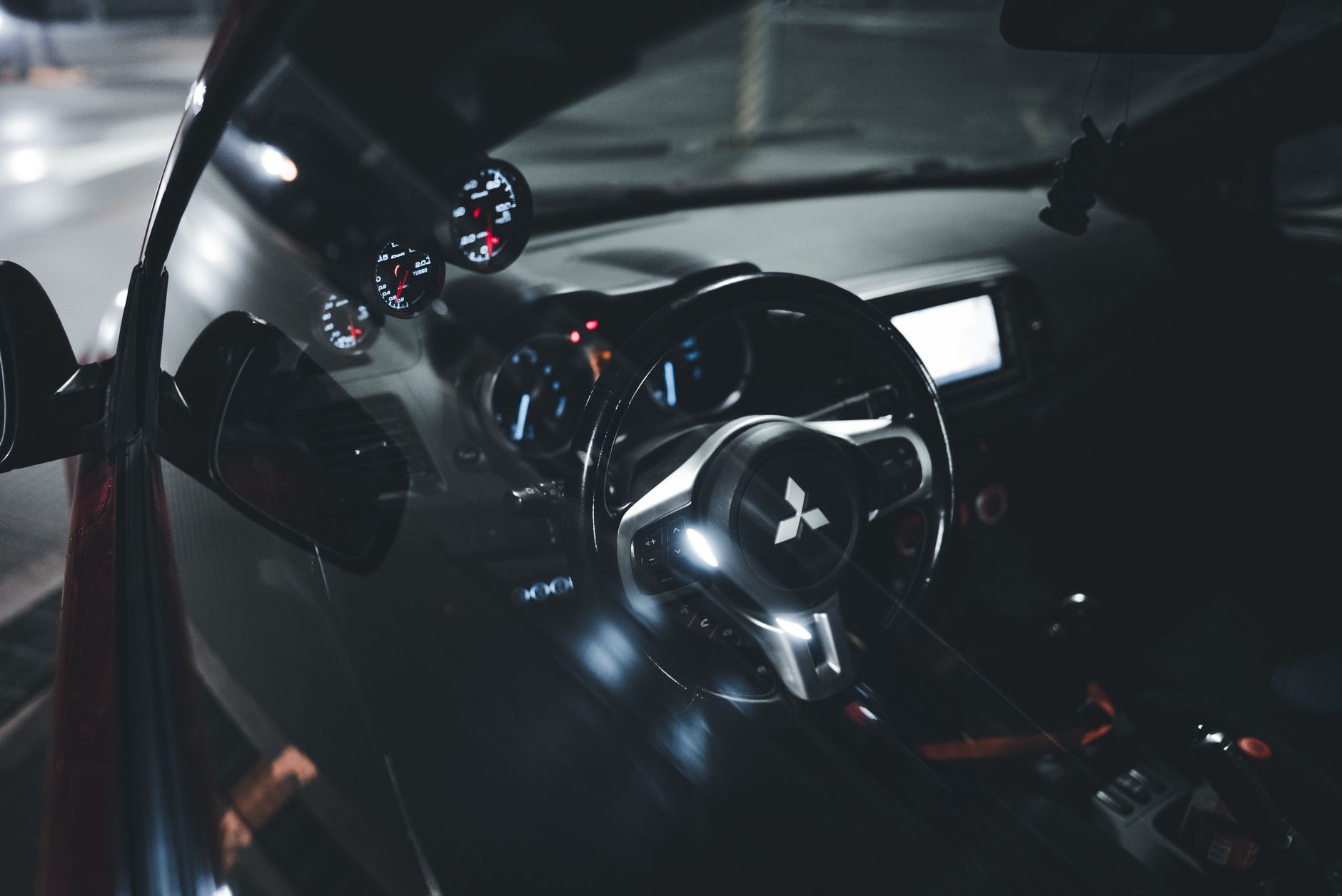 Ilustrasi: A sleek Mitsubishi car interior showcasing an illuminated dashboard and steering wheel, captured malam hari.