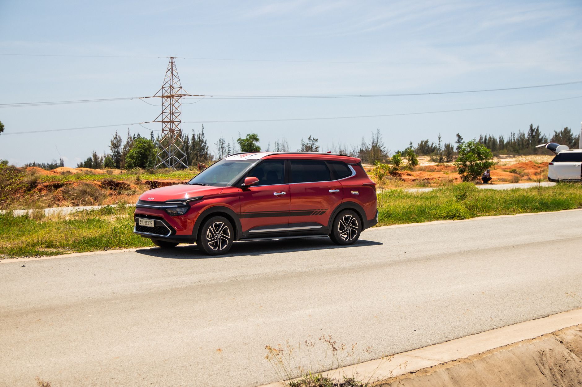 Ilustrasi: A red SUV driving on a sunny road in Phan Thiet, Vietnam, with a natural backdrop.