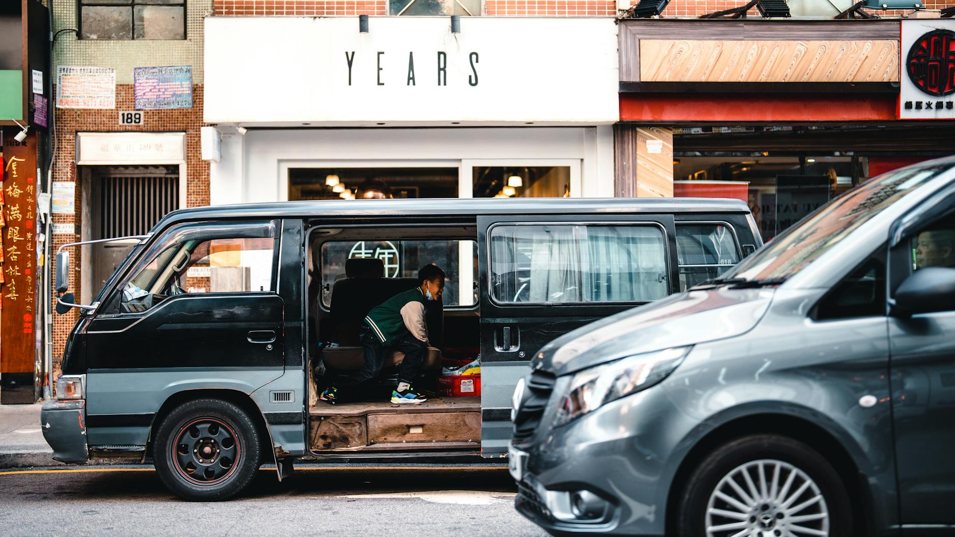 Ilustrasi: A child peeks into a parked minivan on a vibrant city street.