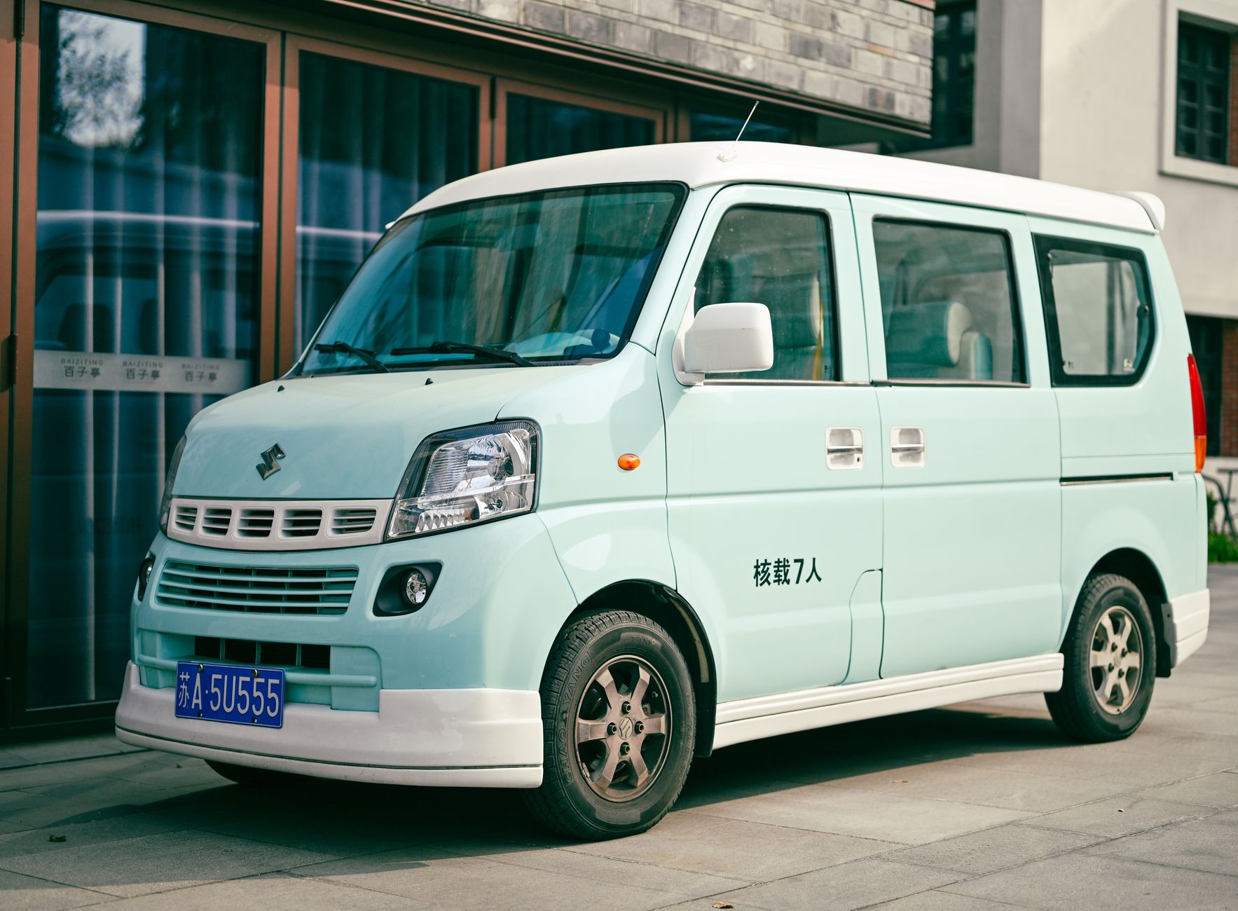 Ilustrasi: A light green Suzuki van parked outdoors in Nanjing, China with license plate visible.