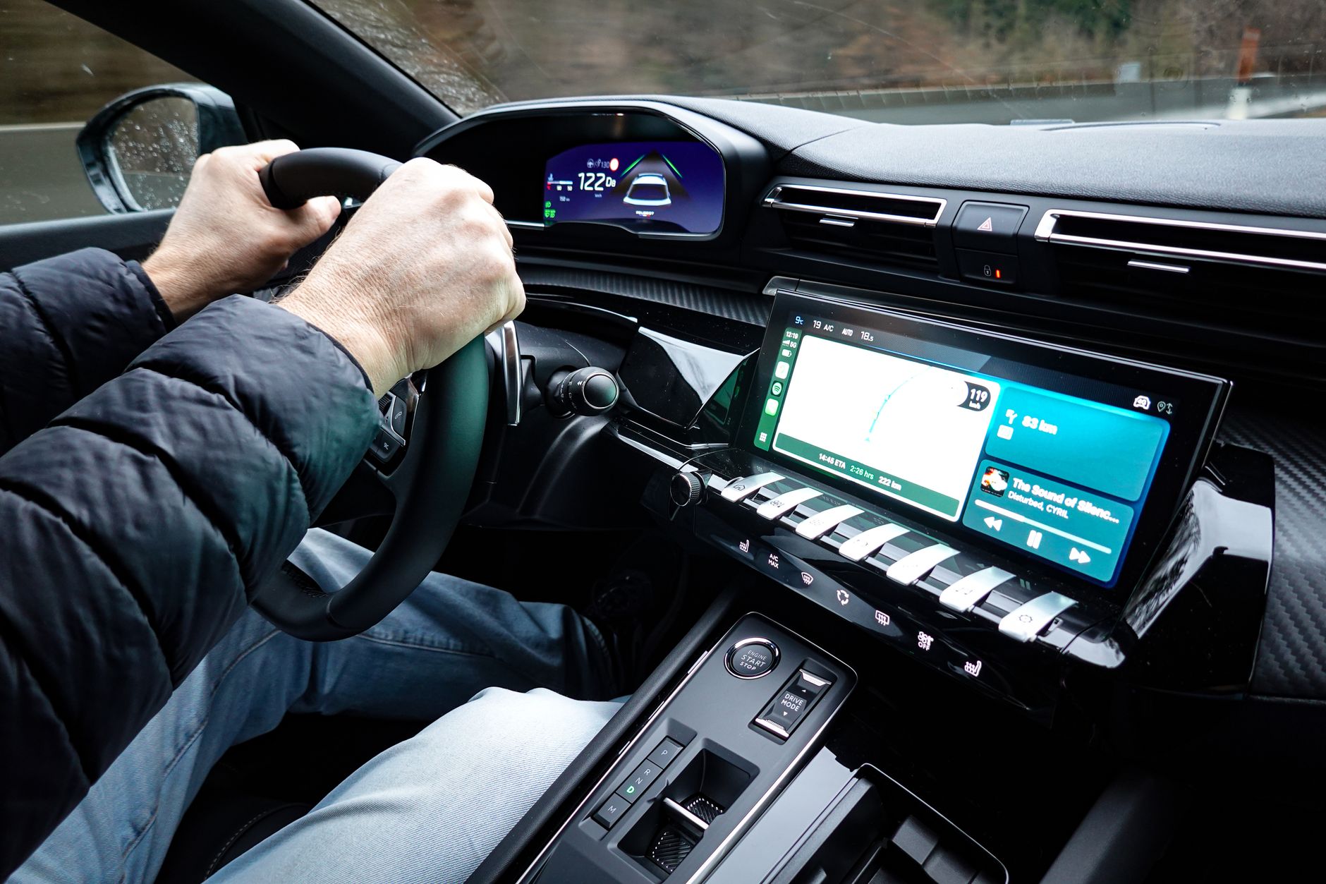 Ilustrasi: A detailed view of a car's interior with hands on the steering wheel, showcasing modern technology.