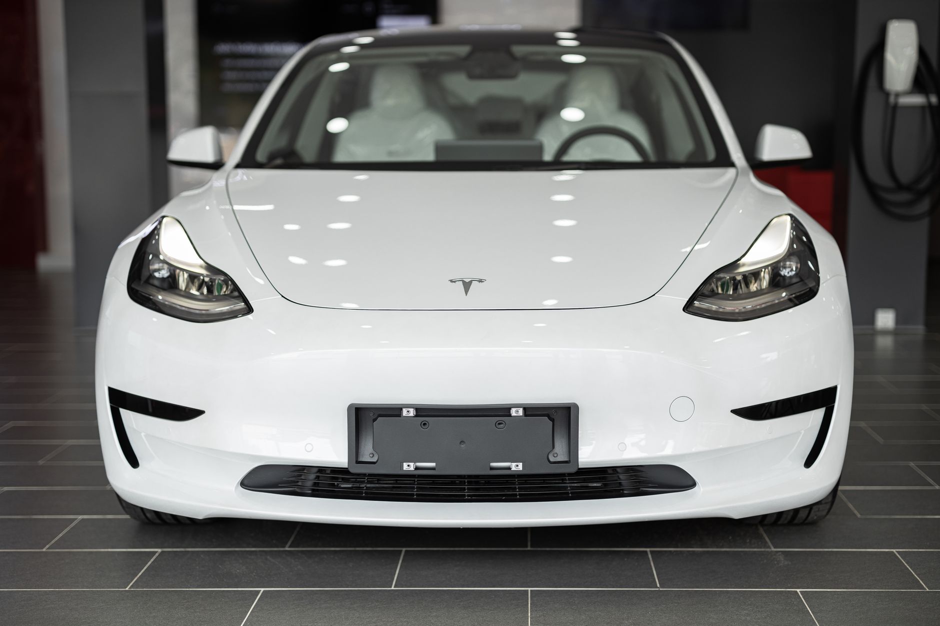 Ilustrasi: Sleek white electric car on display in a modern dealership showroom.