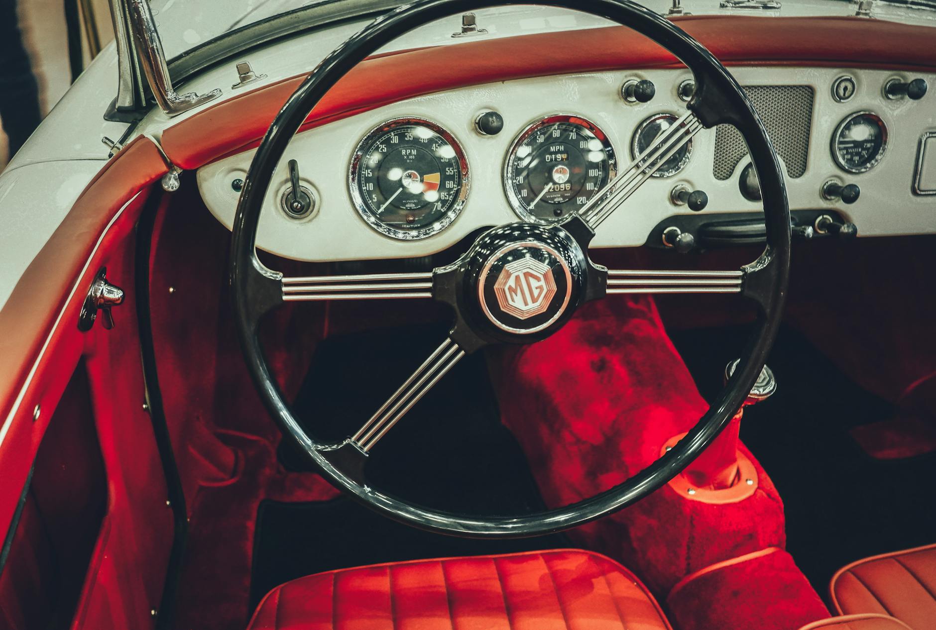 Ilustrasi: Explore the vintage elegance of a classic MG car interior featuring a polished dashboard and luxurious red leather.