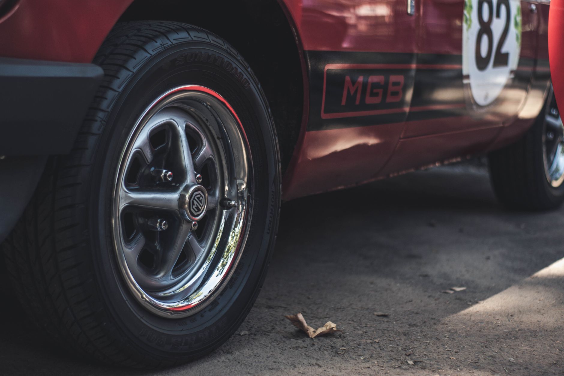 Ilustrasi: Detailed close-up of a classic red MGB car's wheel and rim capturing the vintage design.
