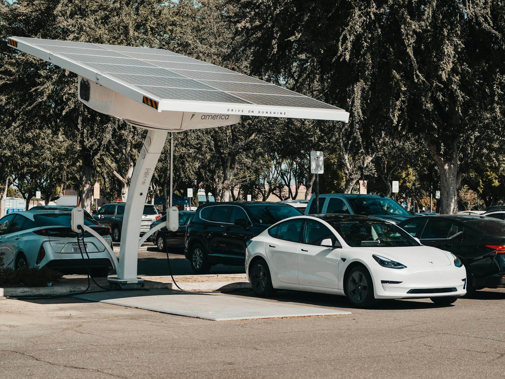 Ilustrasi: Electric car parked at a solar charging station outdoors, highlighting renewable energy and innovation.