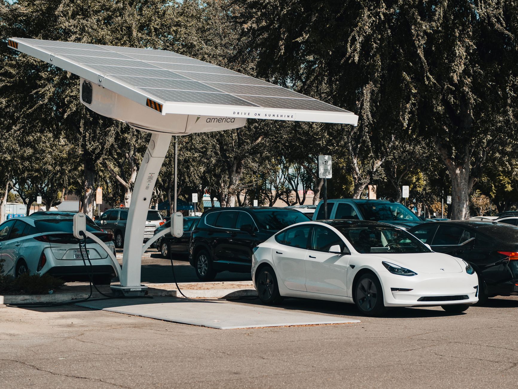 Ilustrasi: Electric car parked at a solar charging station outdoors, highlighting renewable energy and innovation.