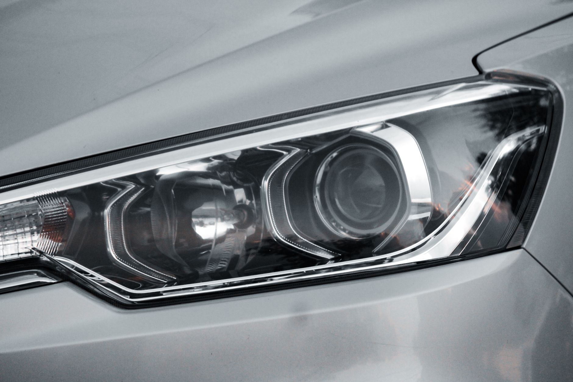 Ilustrasi: Detailed close-up of an elegant car headlight on a sleek vehicle.