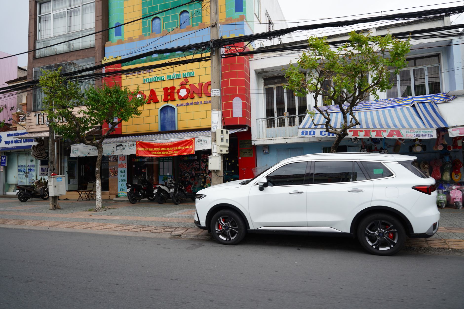 Ilustrasi: A vibrant urban street scene featuring a white SUV parked beside colorful buildings with vivid facades.