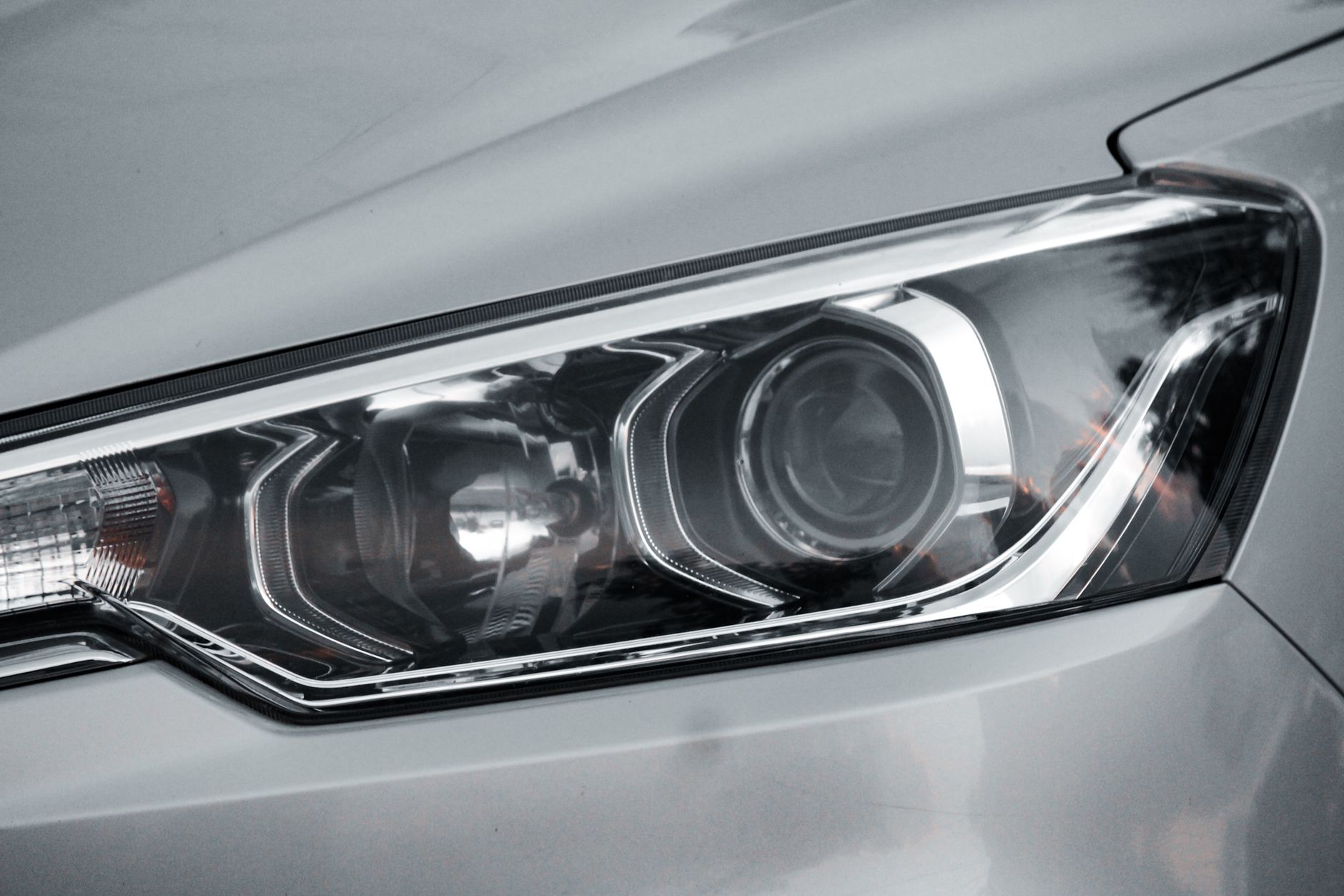 Ilustrasi: Detailed close-up of an elegant car headlight on a sleek vehicle.