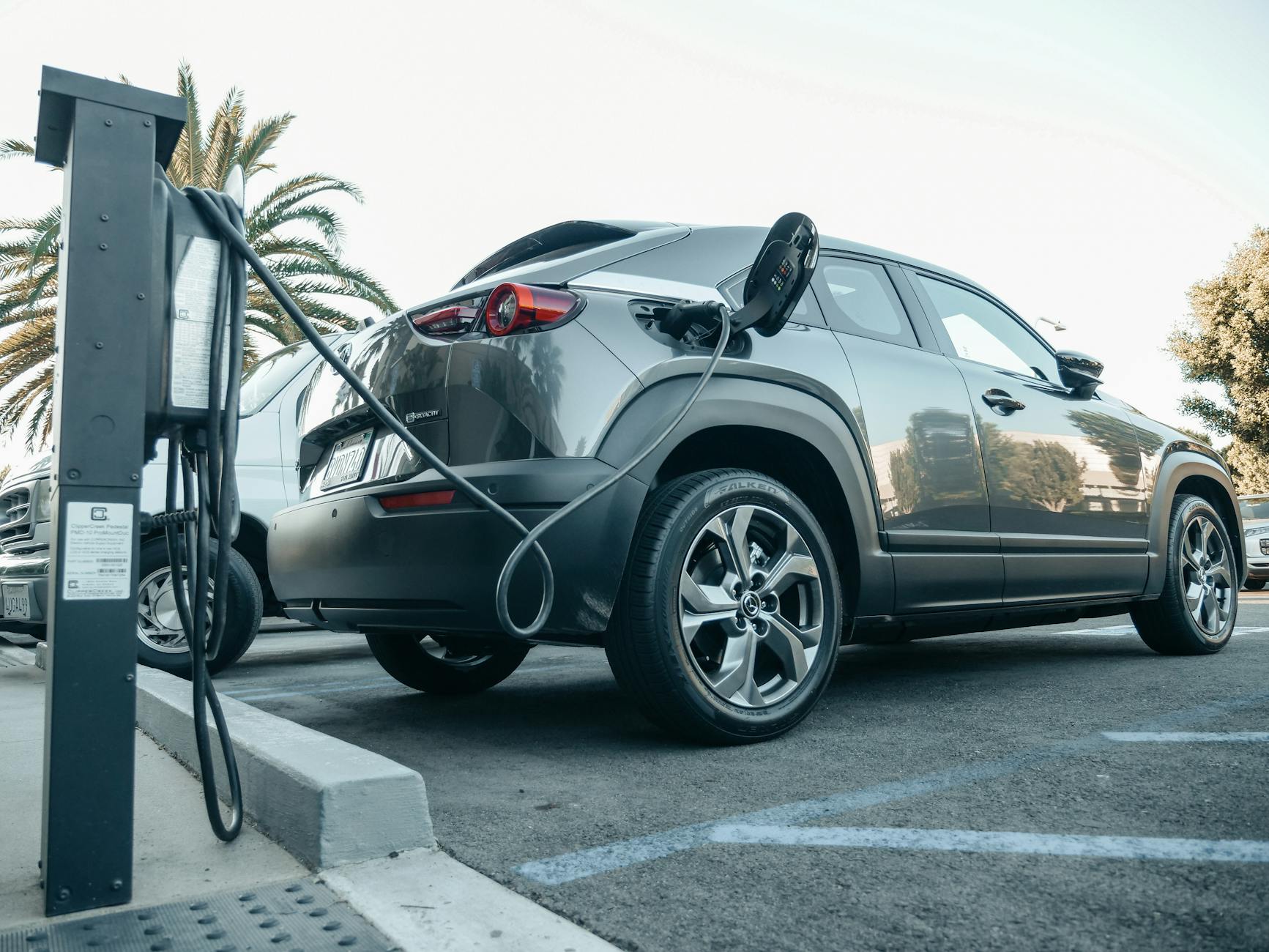 Ilustrasi: Modern electric vehicle charging at an outdoor station in daylight.