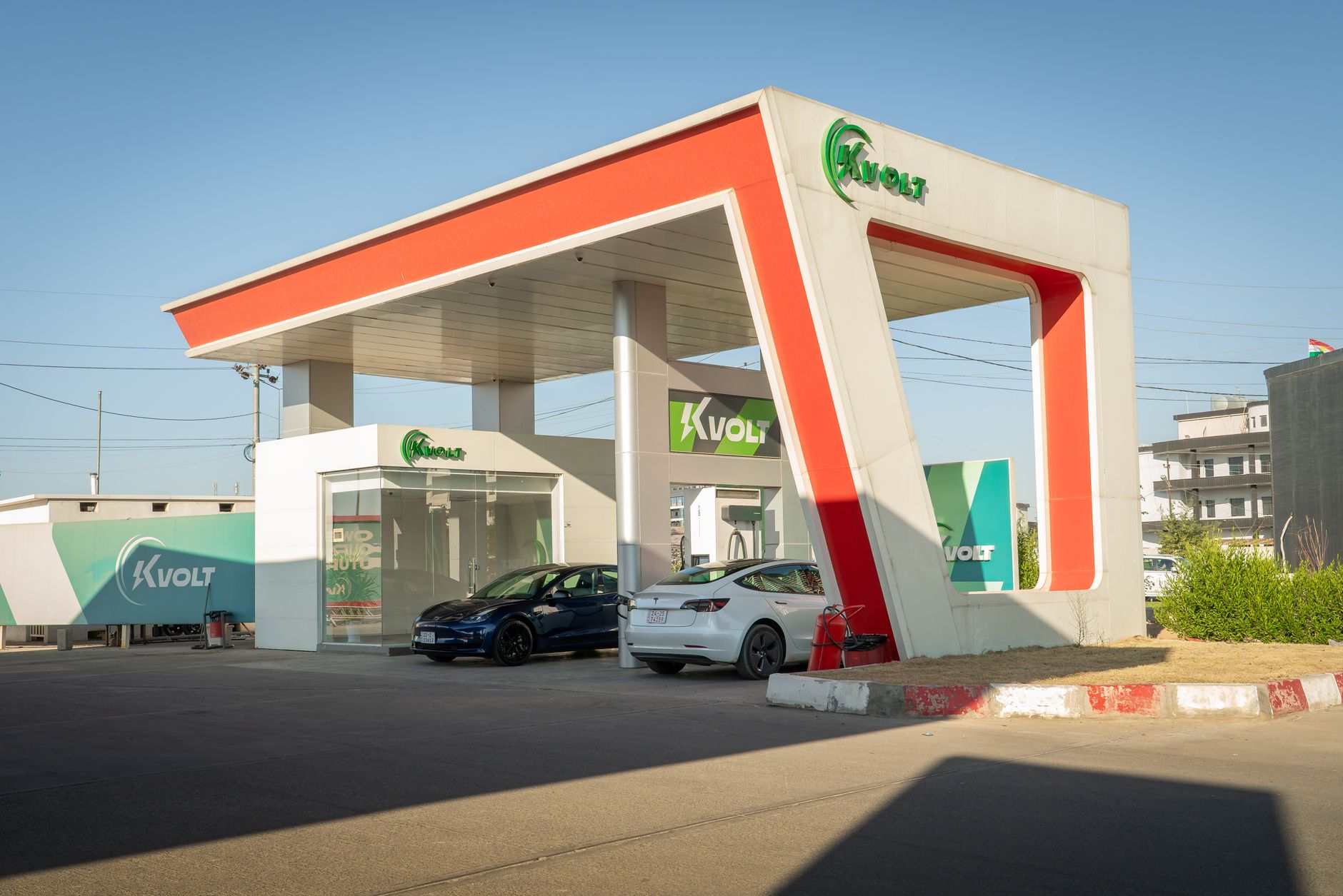 Ilustrasi: A futuristic electric vehicle charging station featuring Tesla cars under a bright blue sky.