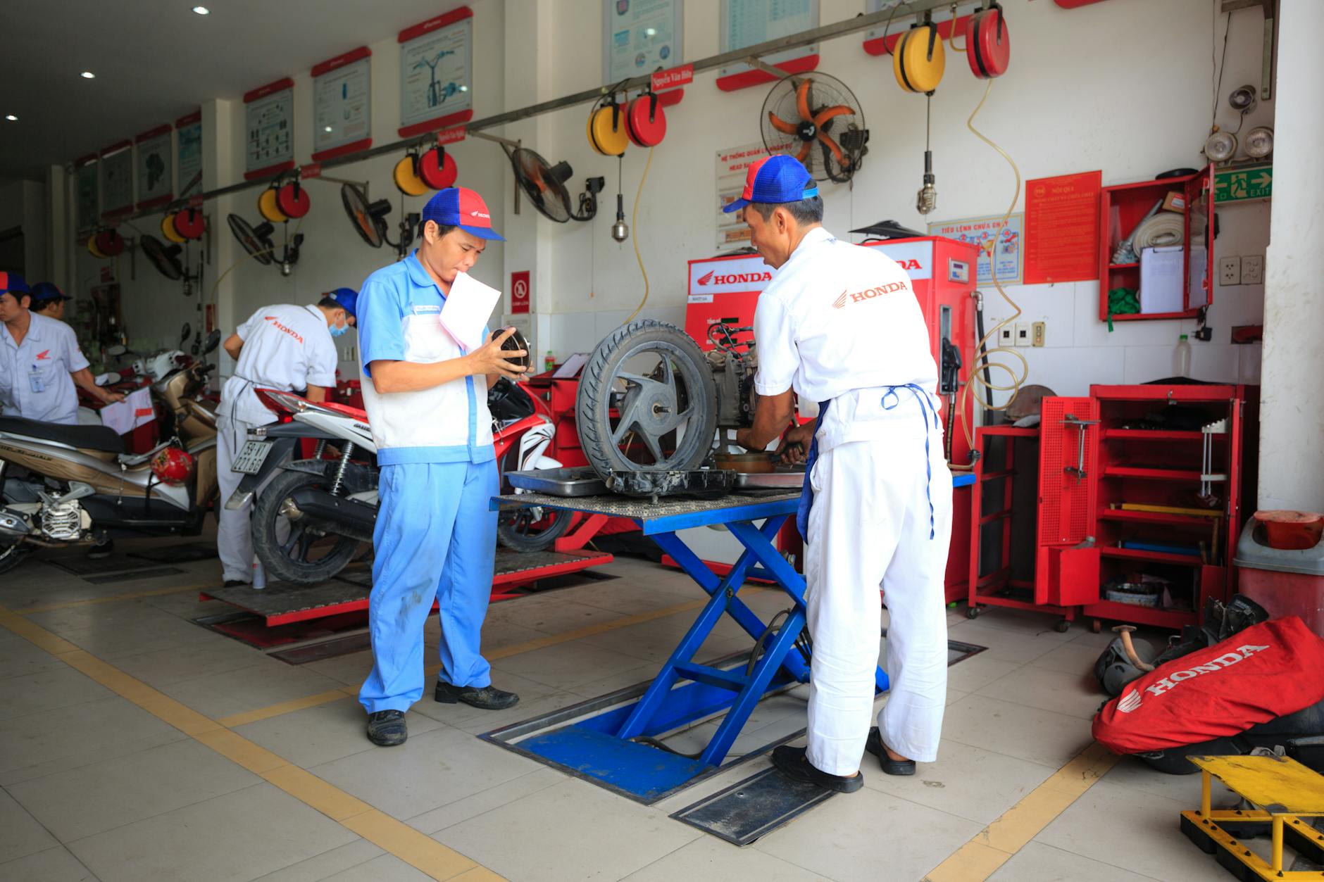 Ilustrasi: Mechanics wearing uniforms work on motorcycles inside a Honda service center.